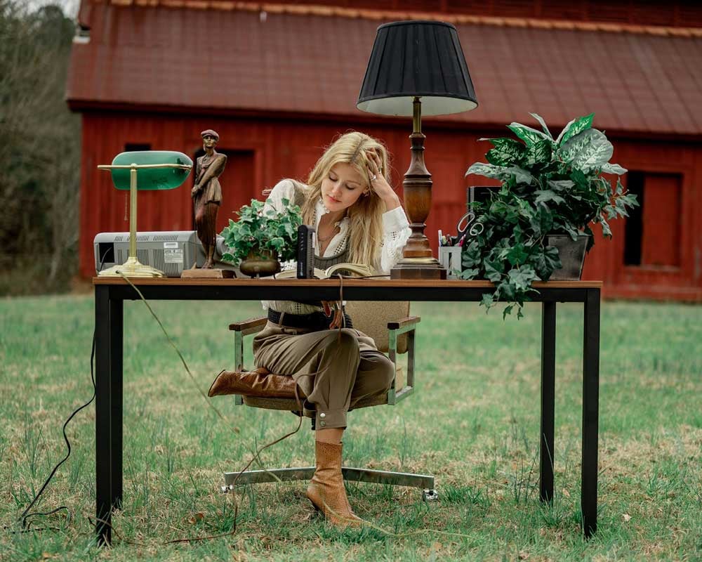 An outdoor scene featuring a woman working at a desk.