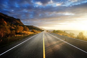 Road between mountains and the sea at sunset