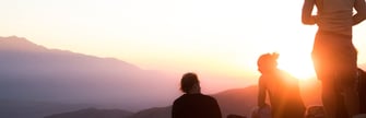 People on mountain watching sunset