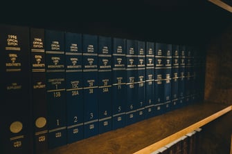 A row of dark blue law books aligned on a wooden shelf.