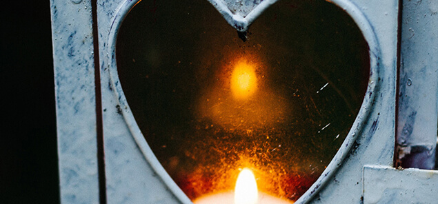 A lantern with a heart-shaped opening with a candle inside.