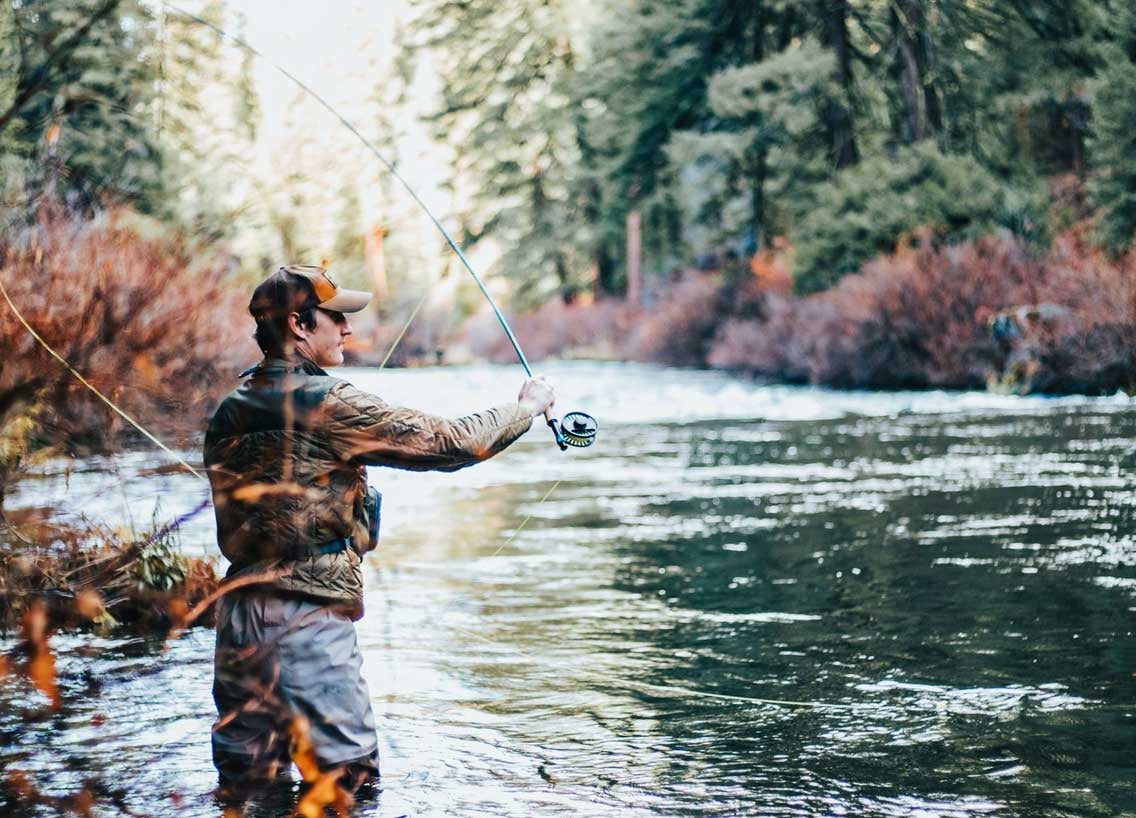 Person standing in a river fishing.